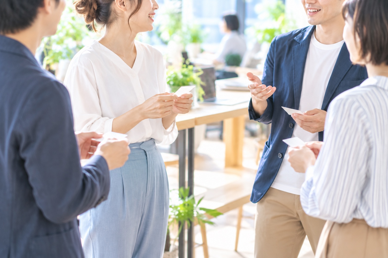 コワーキングスペースの交流会で、名刺を手にフリーランス同士が立ち話をしている様子