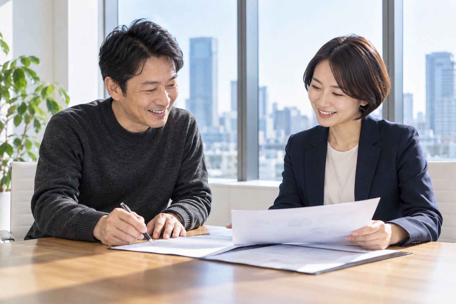 オフィスビルの明るい会議室で、取引先の担当者と契約書を確認しながら笑顔で話す40代の男性フリーランス